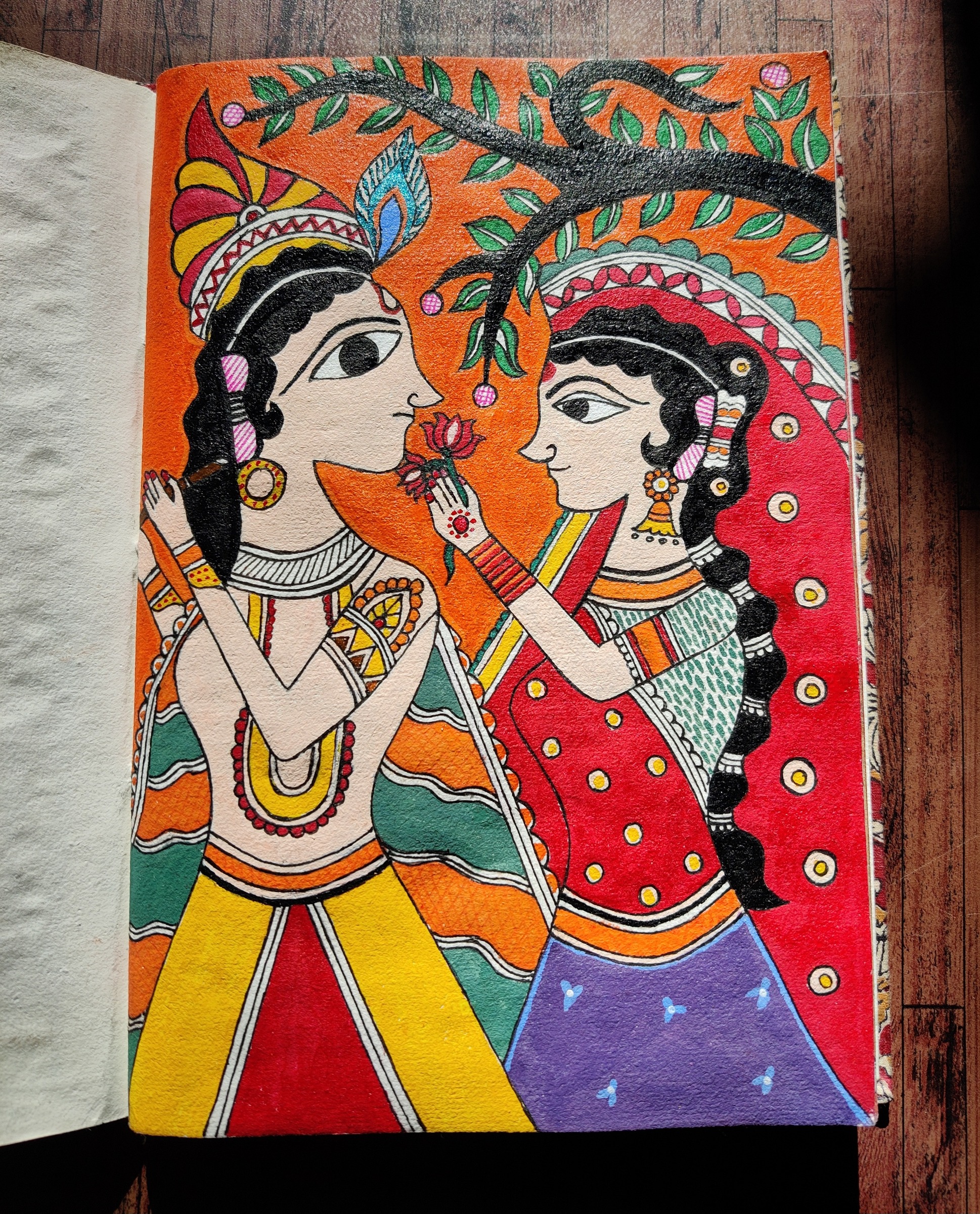 Radha and Krishna meeting beneath a flowering tree, in classical Madhubani style.